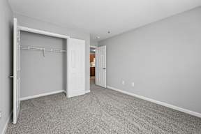 A room with a white door and a grey carpet.